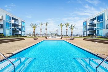 a swimming pool with apartments and palm trees in the background  at Marina Harbor, Marina del Rey, 90292